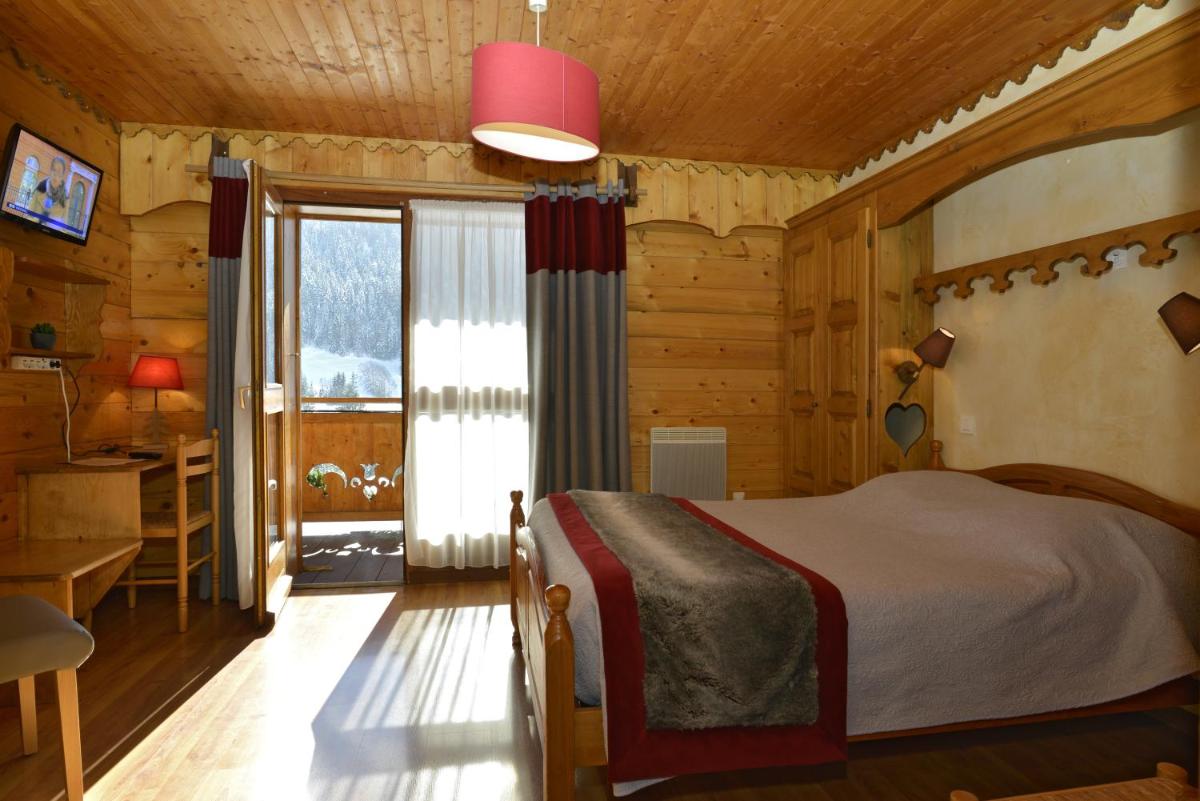 une chambre avec un lit dans une pièce aux murs en bois dans l'établissement Hotel Le Ferraillon, à Abondance