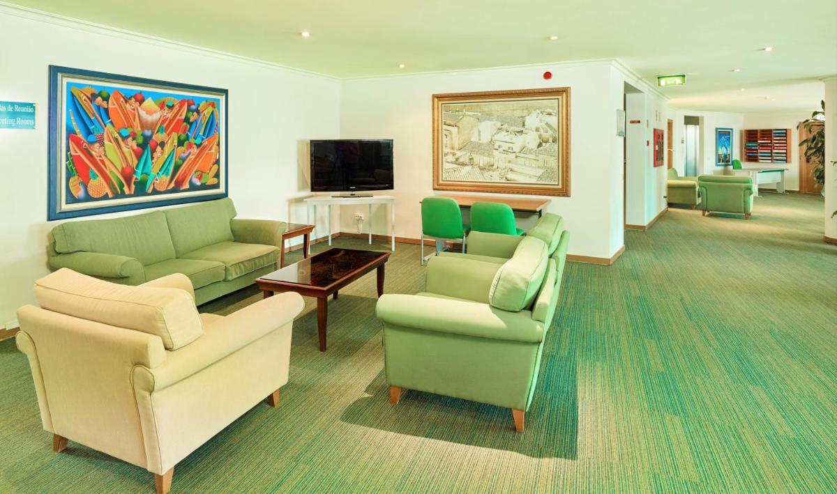 uma sala de estar com sofás e cadeiras e uma televisão em Hotel Baia Grande em Albufeira