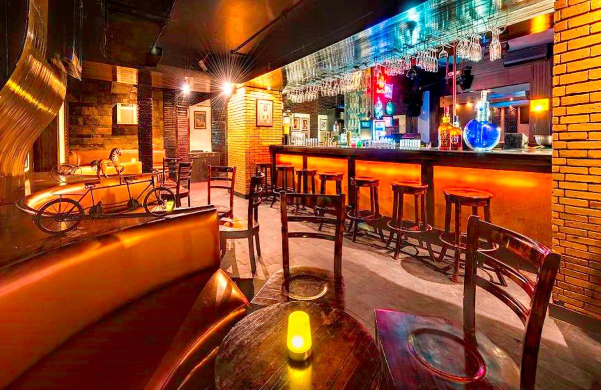 a restaurant with a bar with a wooden table and chairs at Hotel Hindusthan International, Kolkata in Kolkata