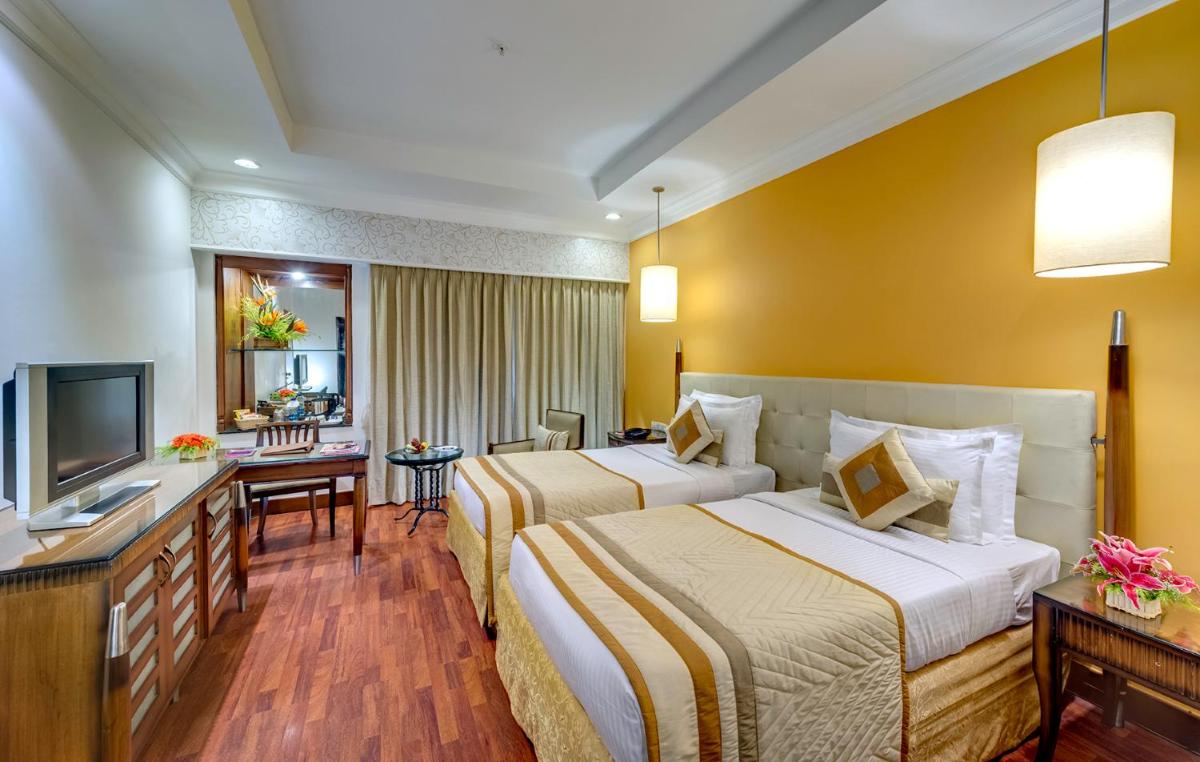 a hotel room with two beds and a television at Hotel Hindusthan International, Kolkata in Kolkata