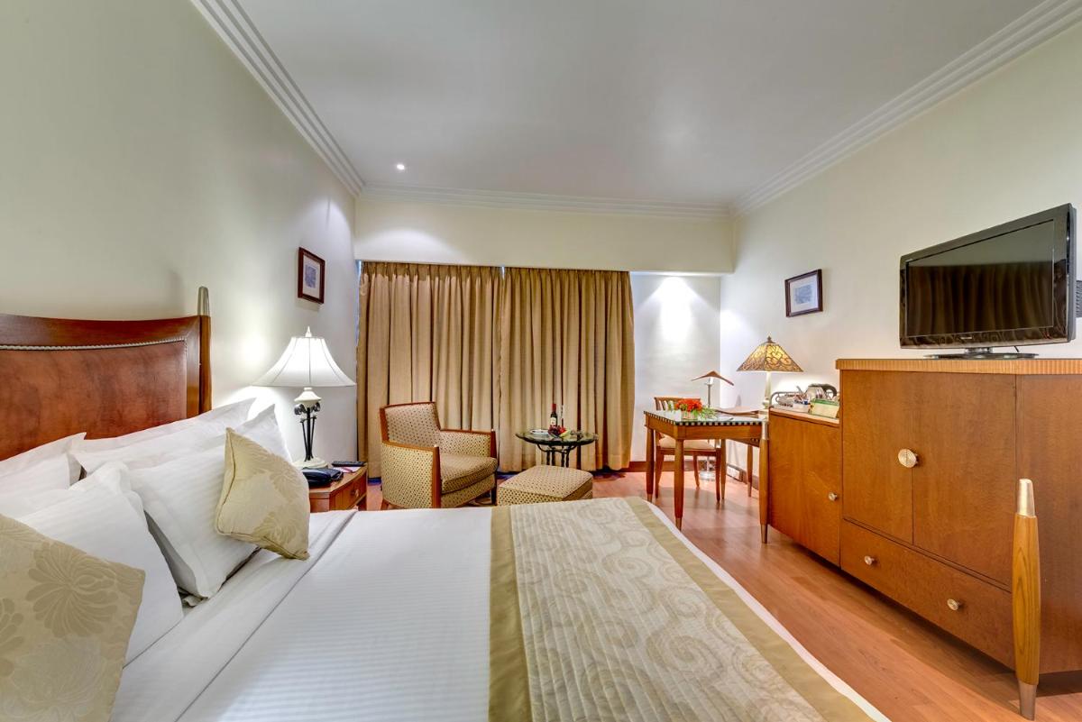 a hotel room with a bed and a living room at Hotel Hindusthan International, Kolkata in Kolkata