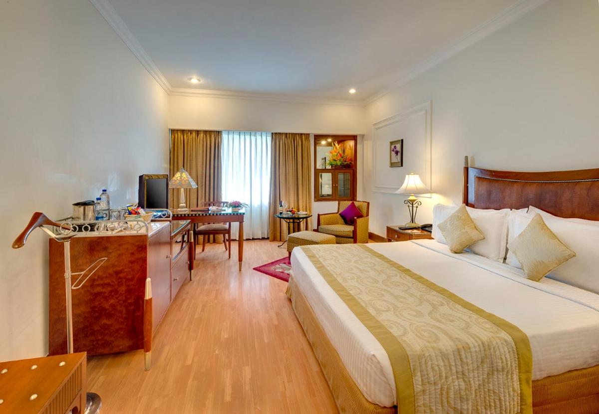a hotel room with a large bed and a desk at Hotel Hindusthan International, Kolkata in Kolkata