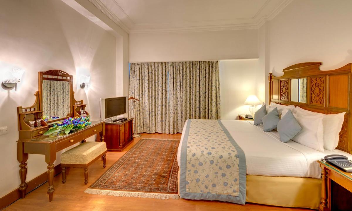 a hotel room with a bed and a desk and a computer at Hotel Hindusthan International, Kolkata in Kolkata