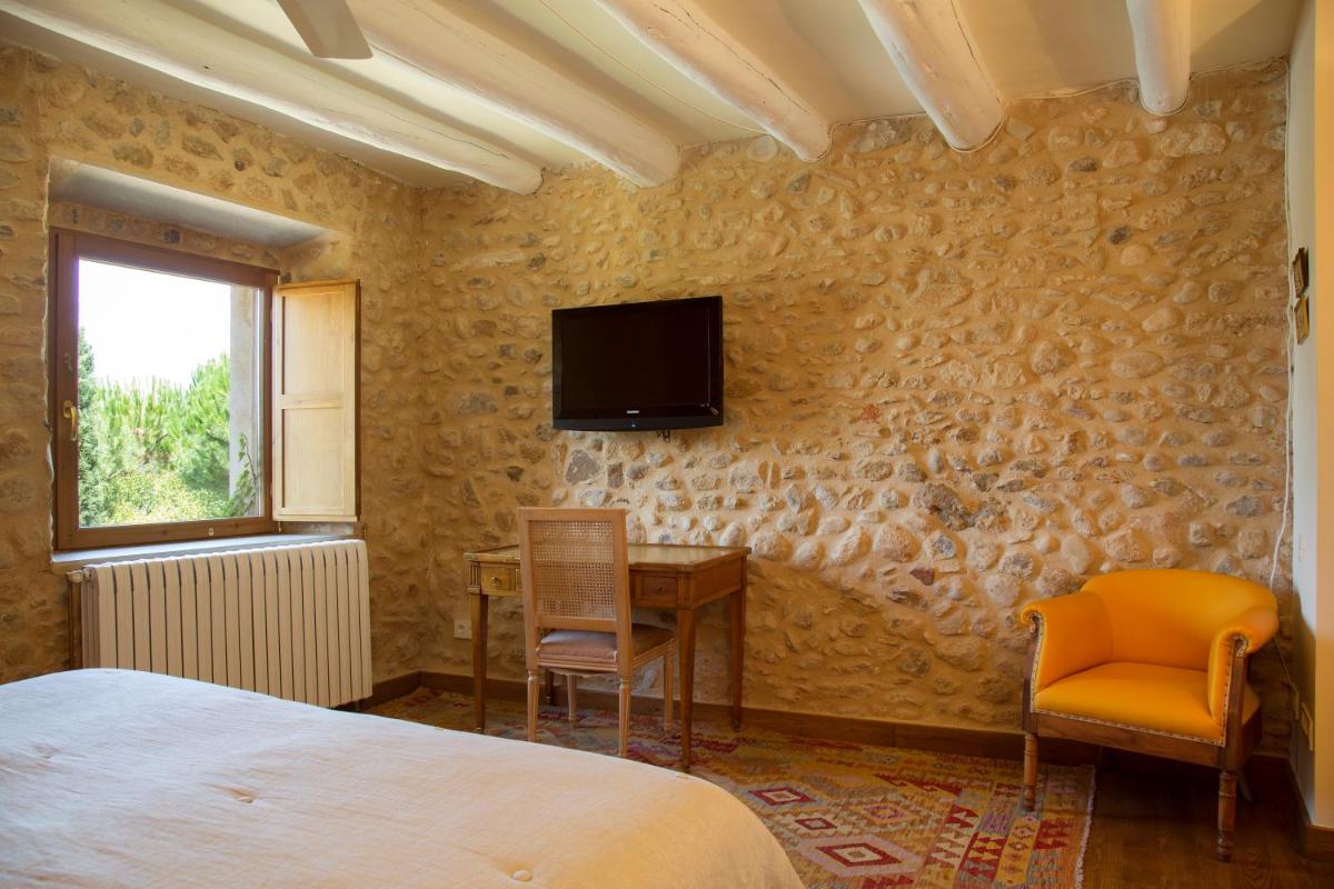Un dormitorio con una cama, un escritorio y un televisor. en Casa Anamaria Hotel, en Ollers