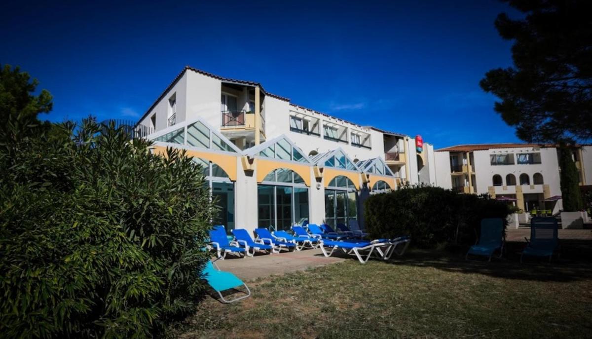 un bâtiment avec des chaises bleues devant dans l'établissement ibis Sète Balaruc les Bains Bien-être et Spa, à Balaruc-les-Bains