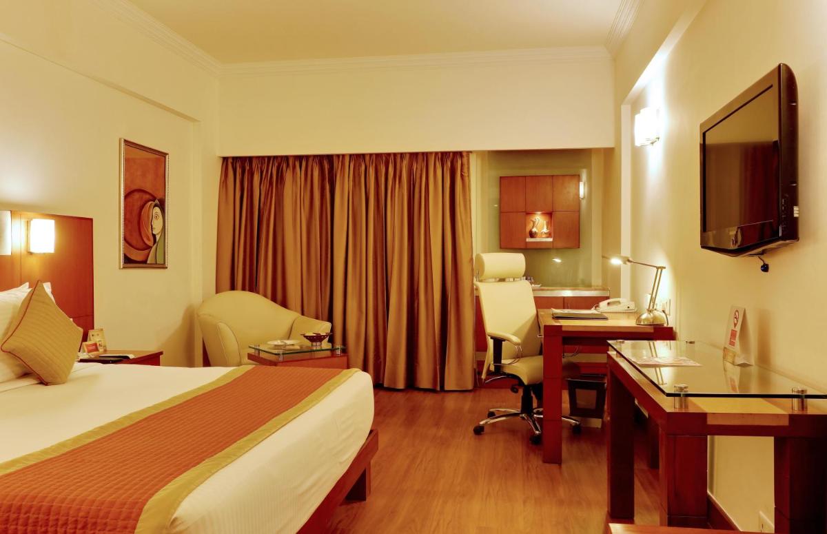 a hotel room with a bed and a desk at The Suryaa New Delhi in New Delhi a hotel room with a bed and a desk at The Suryaa New Delhi in New Delhi