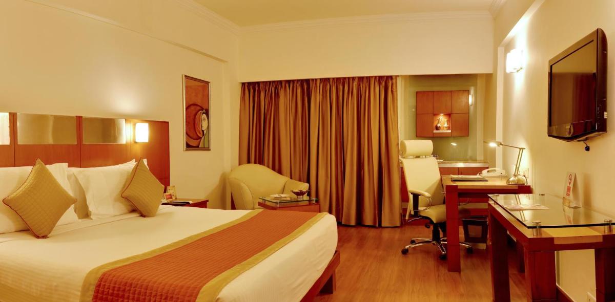 a hotel room with a bed and a desk at The Suryaa New Delhi in New Delhi a hotel room with a bed and a desk at The Suryaa New Delhi in New Delhi
