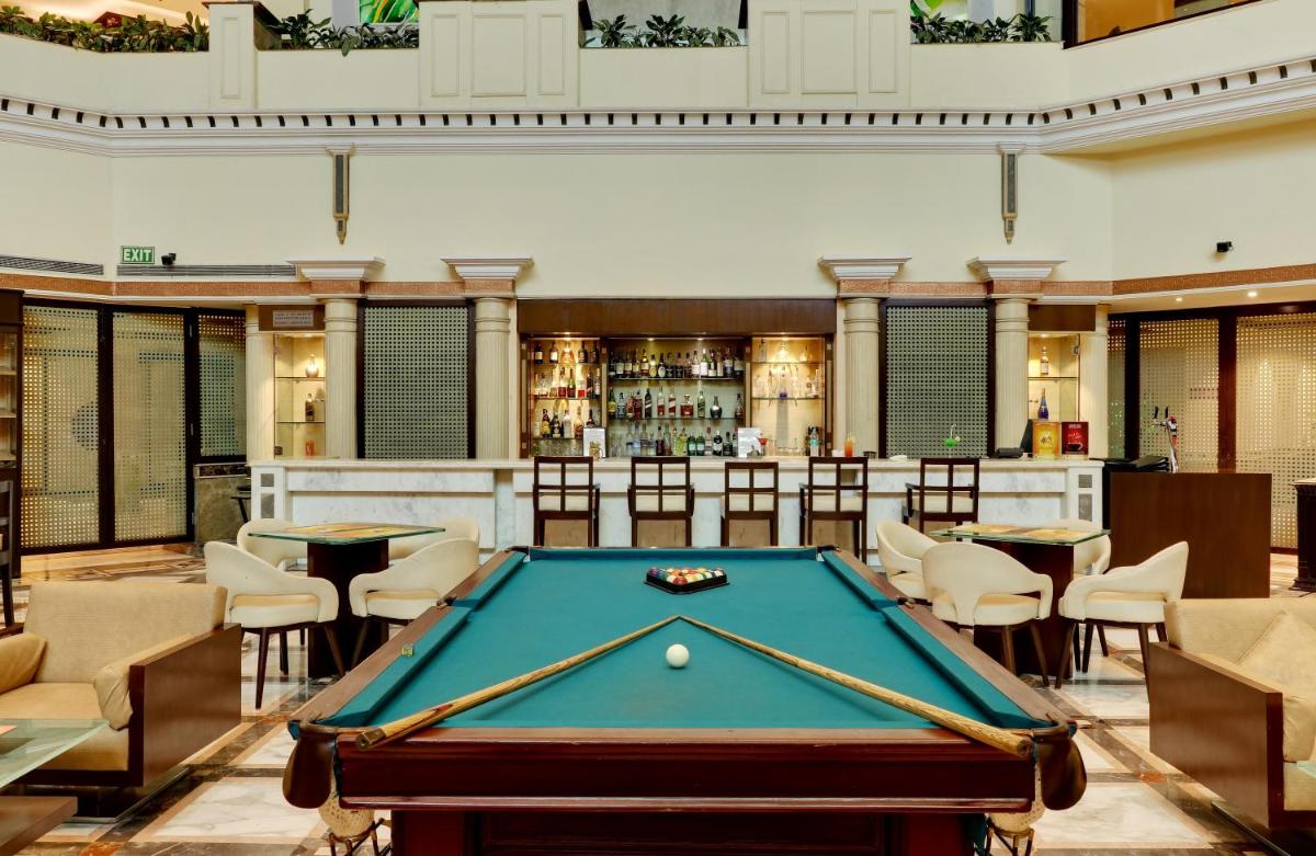 a pool table in a room with a bar at The Suryaa New Delhi in New Delhi a pool table in a room with a bar at The Suryaa New Delhi in New Delhi