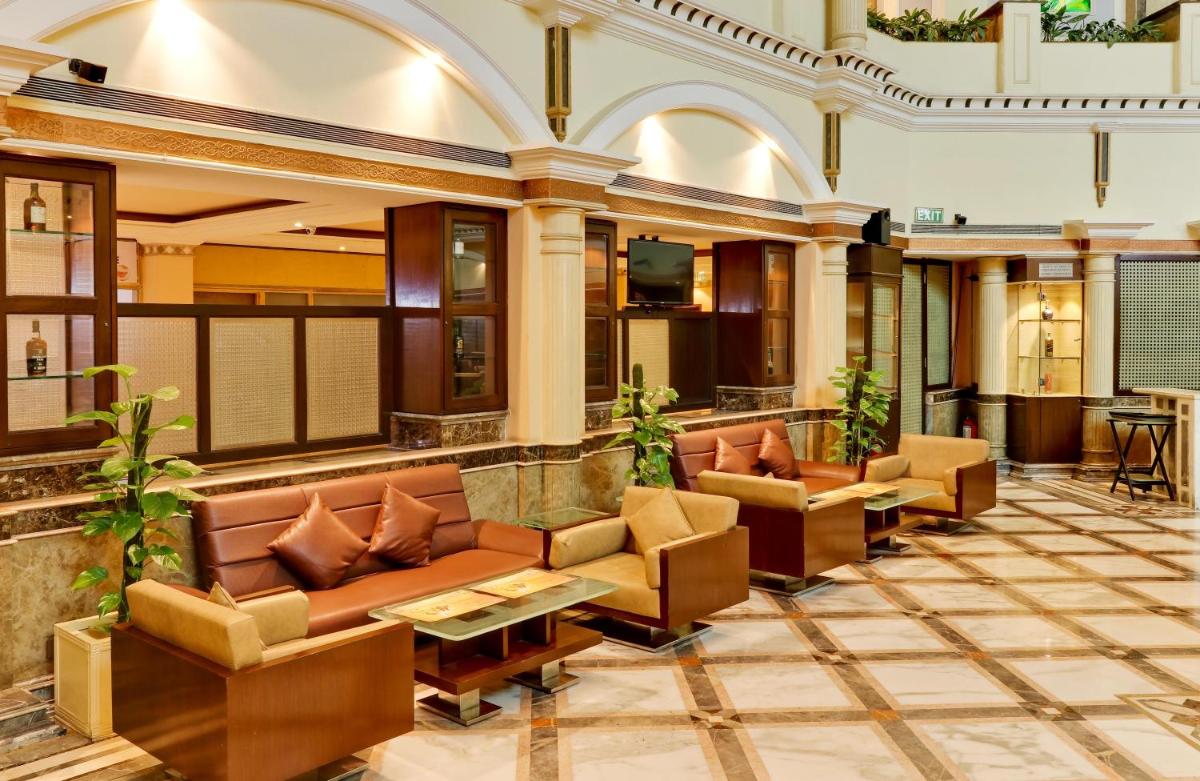 a lobby of a hotel with couches and tables at The Suryaa New Delhi in New Delhi a lobby of a hotel with couches and tables at The Suryaa New Delhi in New Delhi