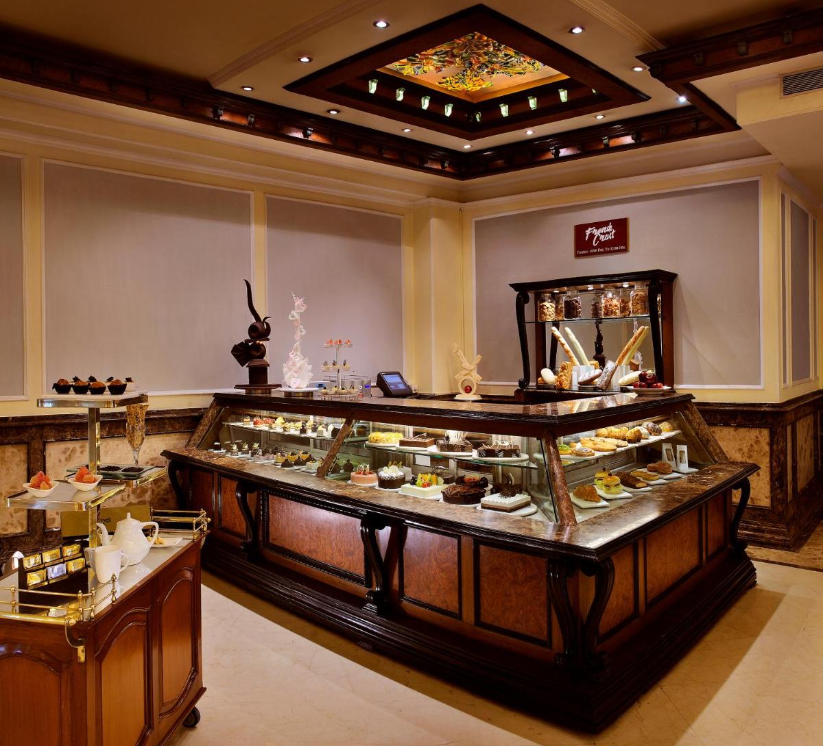 a display case in a restaurant with a lot of desserts at The Suryaa New Delhi in New Delhi a display case in a restaurant with a lot of desserts at The Suryaa New Delhi in New Delhi