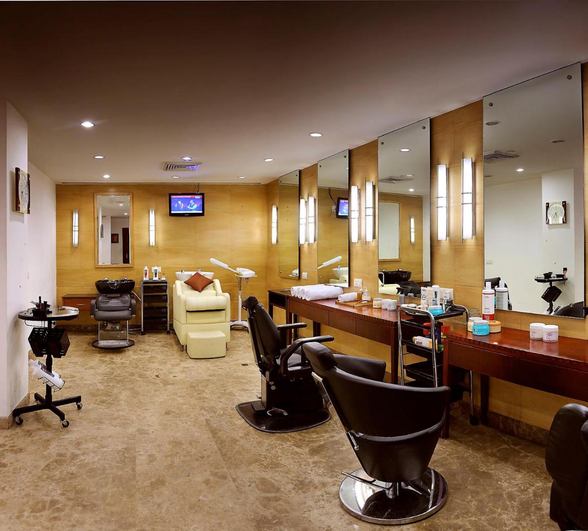 a hair salon with chairs and desks and mirrors at The Suryaa New Delhi in New Delhi a hair salon with chairs and desks and mirrors at The Suryaa New Delhi in New Delhi