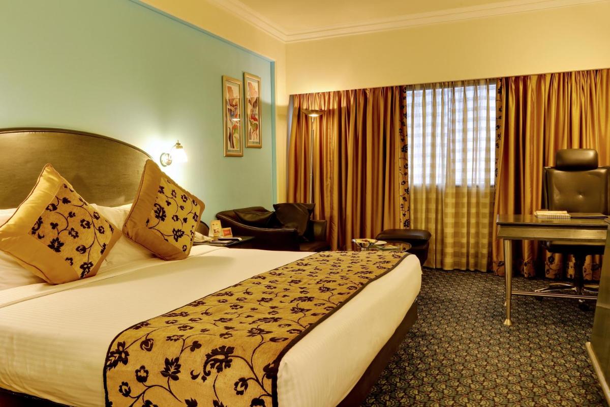 a hotel room with a bed and a desk at The Suryaa New Delhi in New Delhi a hotel room with a bed and a desk at The Suryaa New Delhi in New Delhi