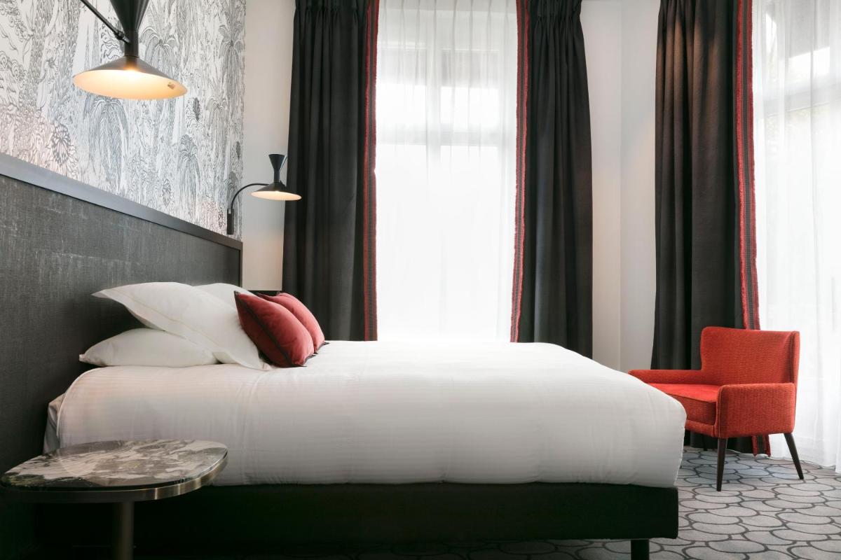 une chambre avec un lit blanc et une chaise rouge dans l'établissement Continental Hotel, à Reims 72 autres photos