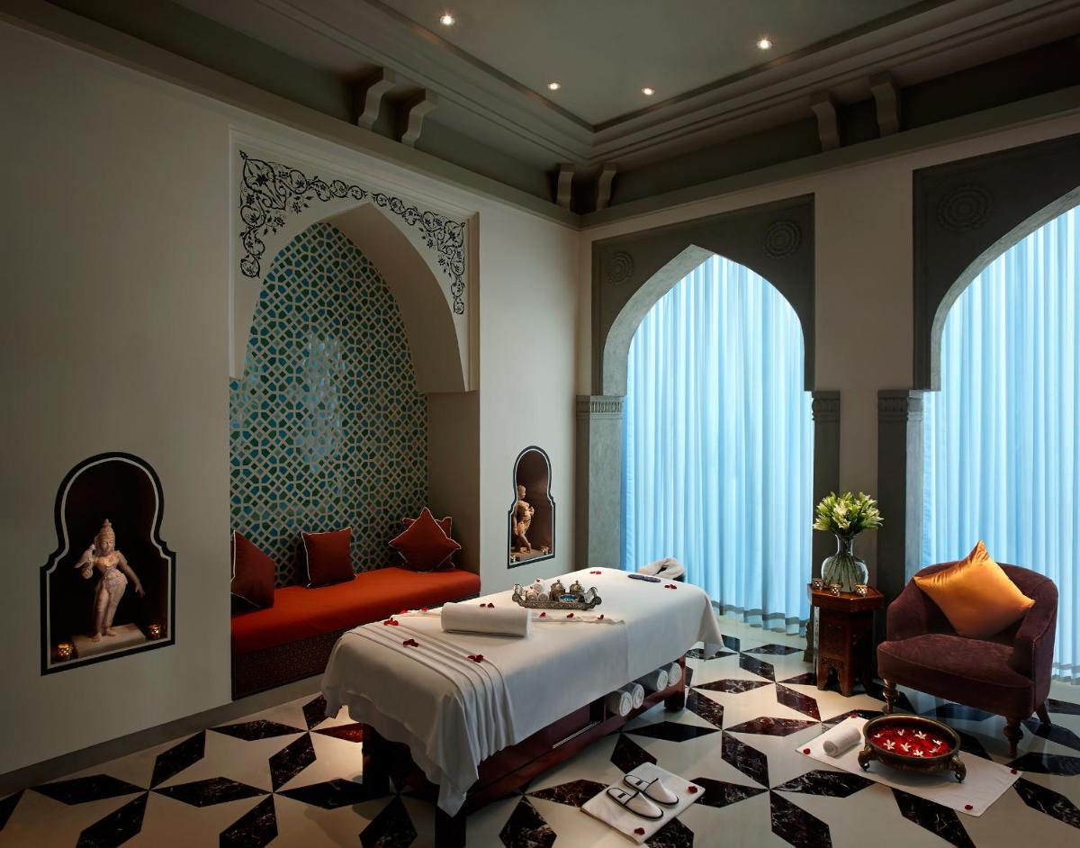 a bedroom with a bed and a couch and windows at Fairmont Jaipur in Jaipur