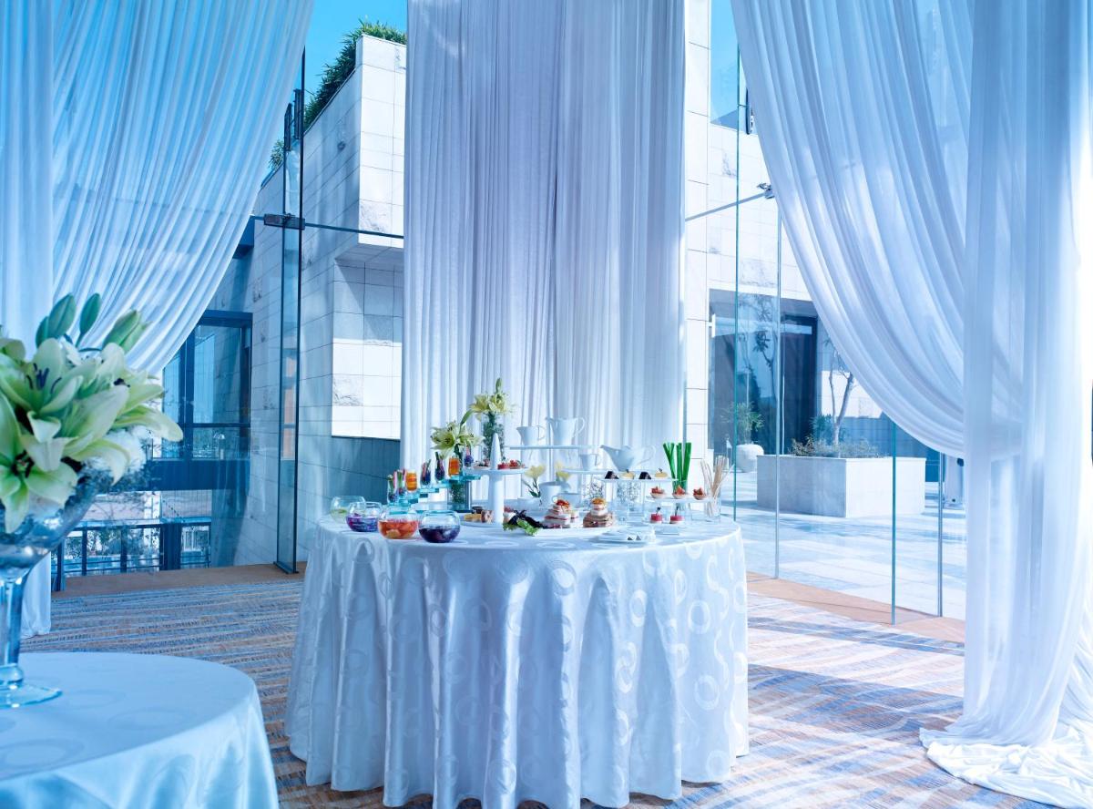 a white table with food on it in a room with windows at Taj City Centre Gurugram in Gurgaon