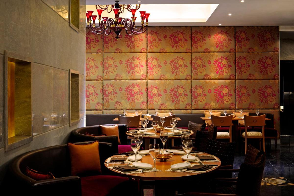 a dining room with tables and chairs and a chandelier at Taj Club House in Chennai