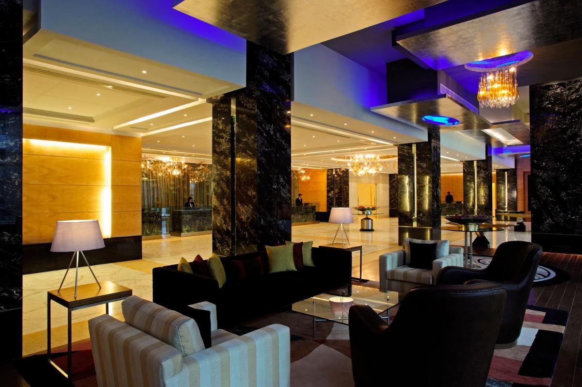 a lobby with couches and tables in a building at Taj Club House in Chennai