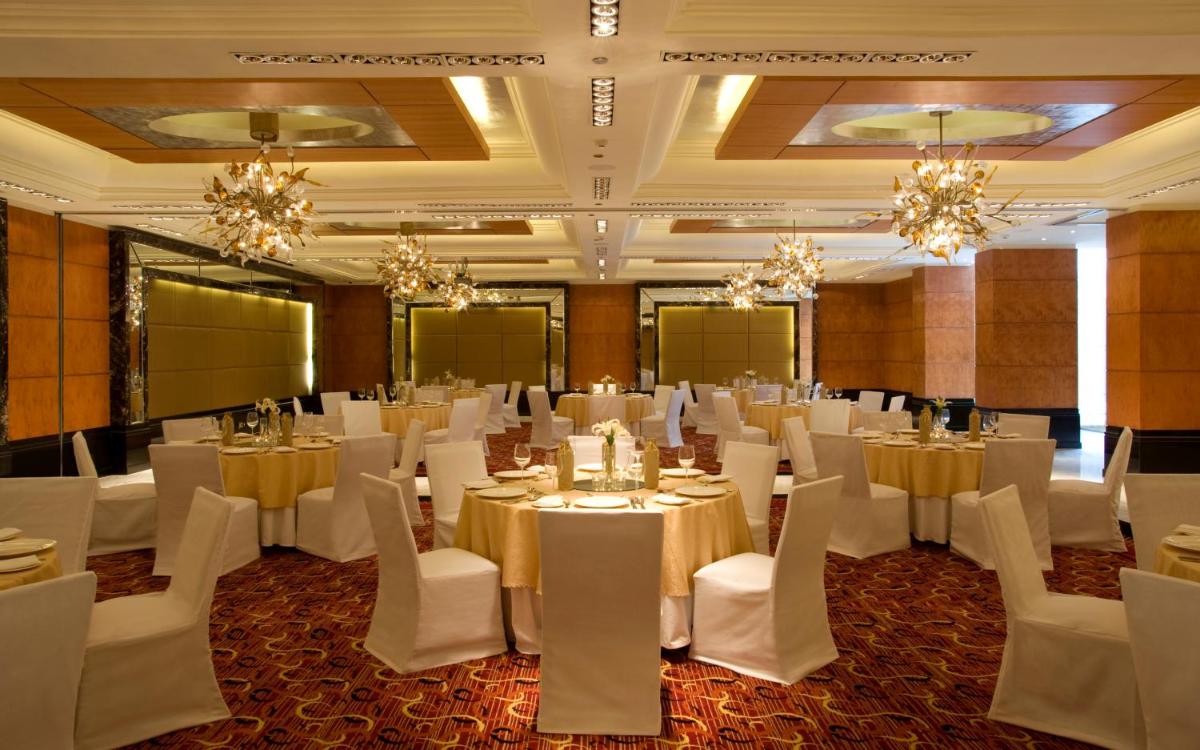 a banquet hall with white tables and chairs and chandeliers at Taj Club House in Chennai