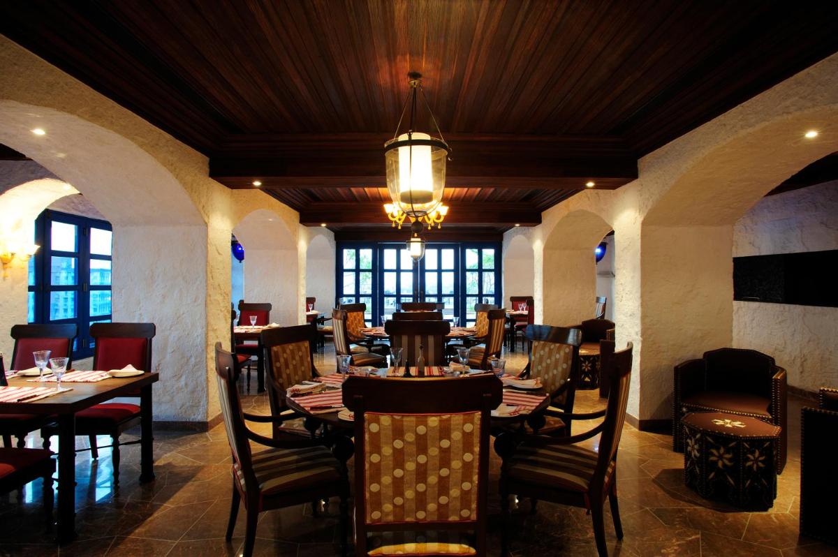 a restaurant with tables and chairs and a chandelier at Taj Club House in Chennai