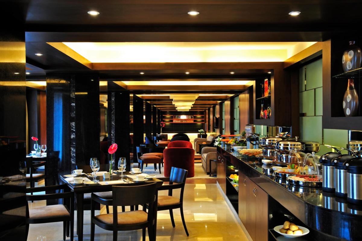 a restaurant with a bar with tables and chairs at Taj Club House in Chennai