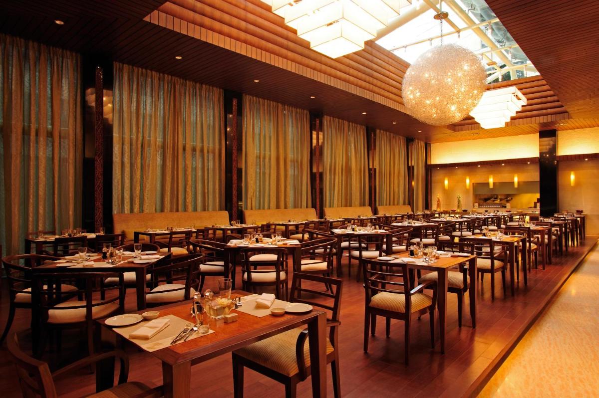 a dining room with tables and chairs and a chandelier at Taj Club House in Chennai