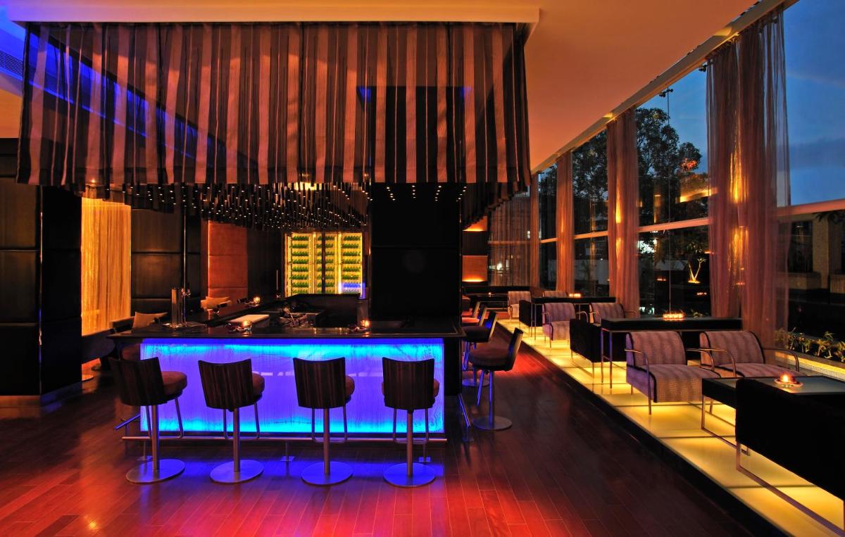 a bar in a restaurant with chairs and tables at Taj Club House in Chennai
