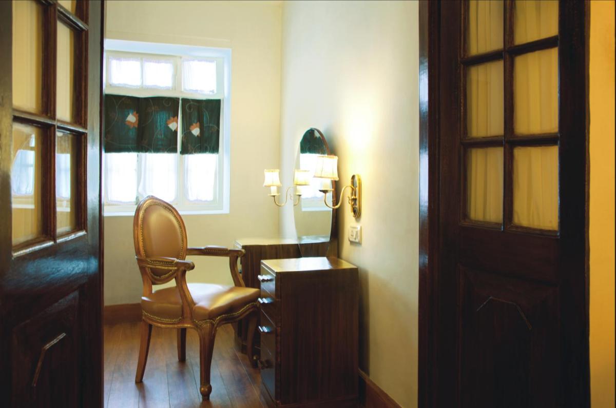 a room with a chair and a table and a window at Savoy - IHCL SeleQtions in Ooty