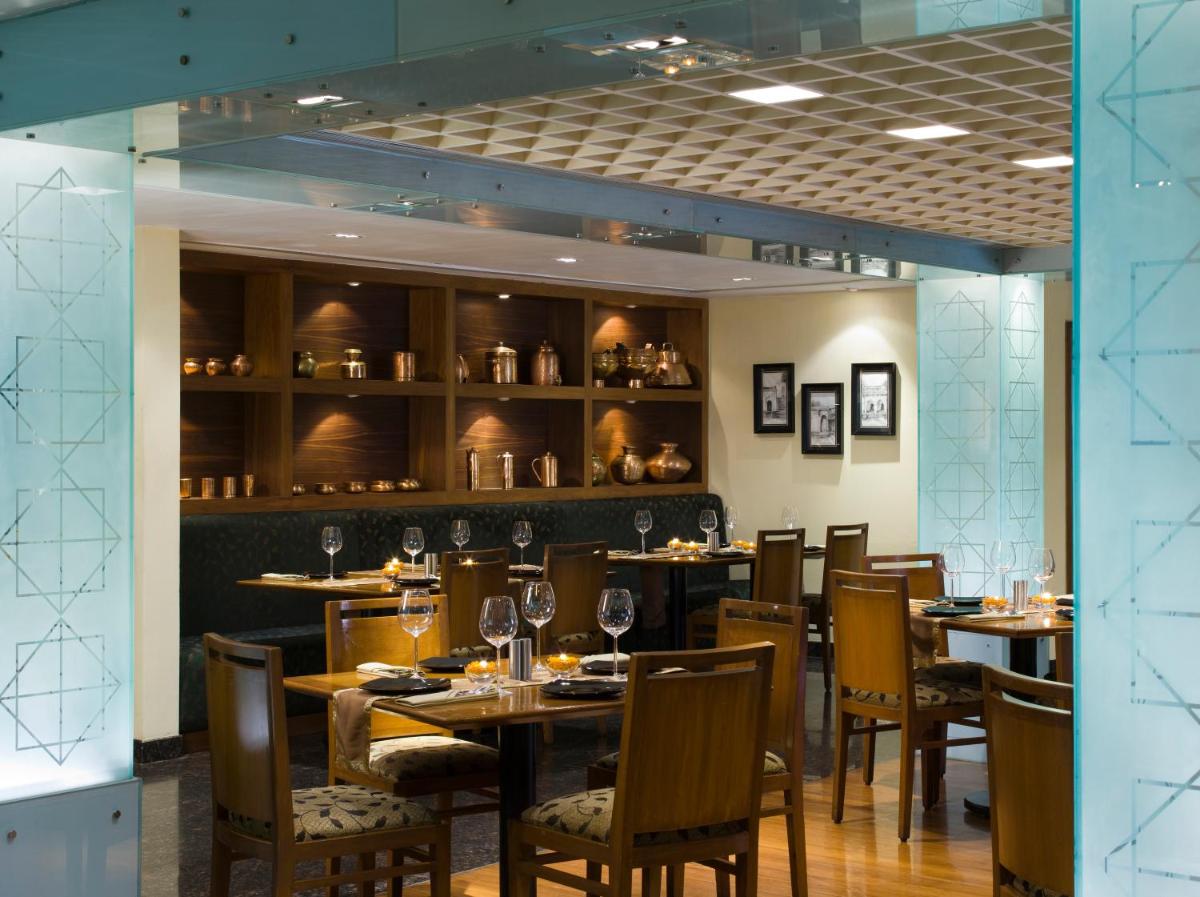 a dining room with tables and chairs with wine glasses at Blue Diamond Pune IHCL SeleQtions in Pune