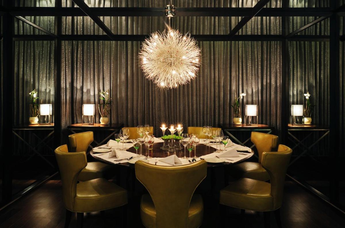 a dining room with a table with chairs and a chandelier at Taj Bengal in Kolkata