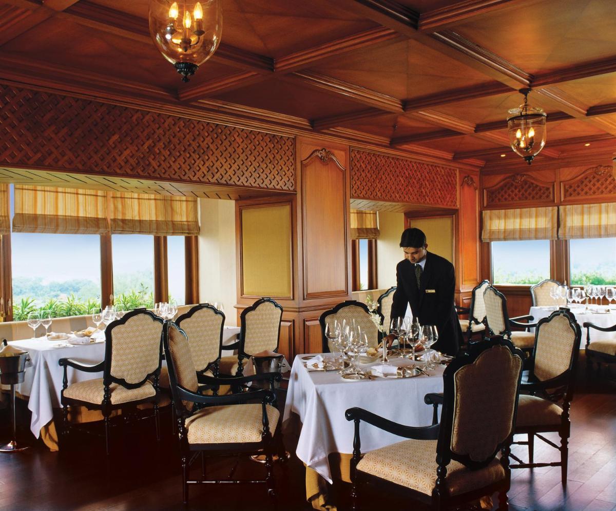 a man standing at a table in a dining room at Taj Bengal in Kolkata