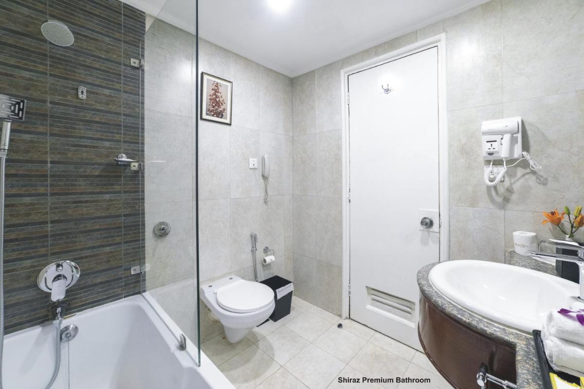 a bathroom with a tub and a toilet and a sink at Hotel Clarks Shiraz in Agra