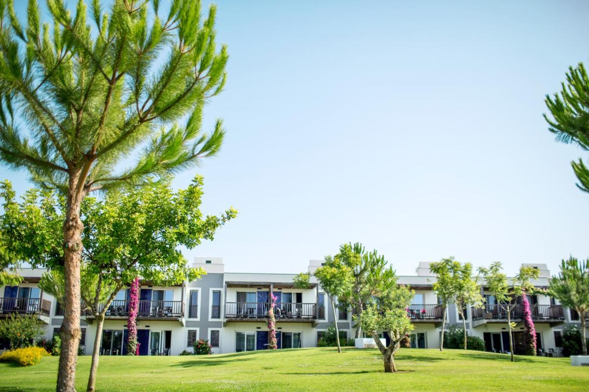 um prédio de apartamentos com árvores em frente em ROBINSON QUINTA DA RIA - All Inclusive em Vila Nova de Cacela