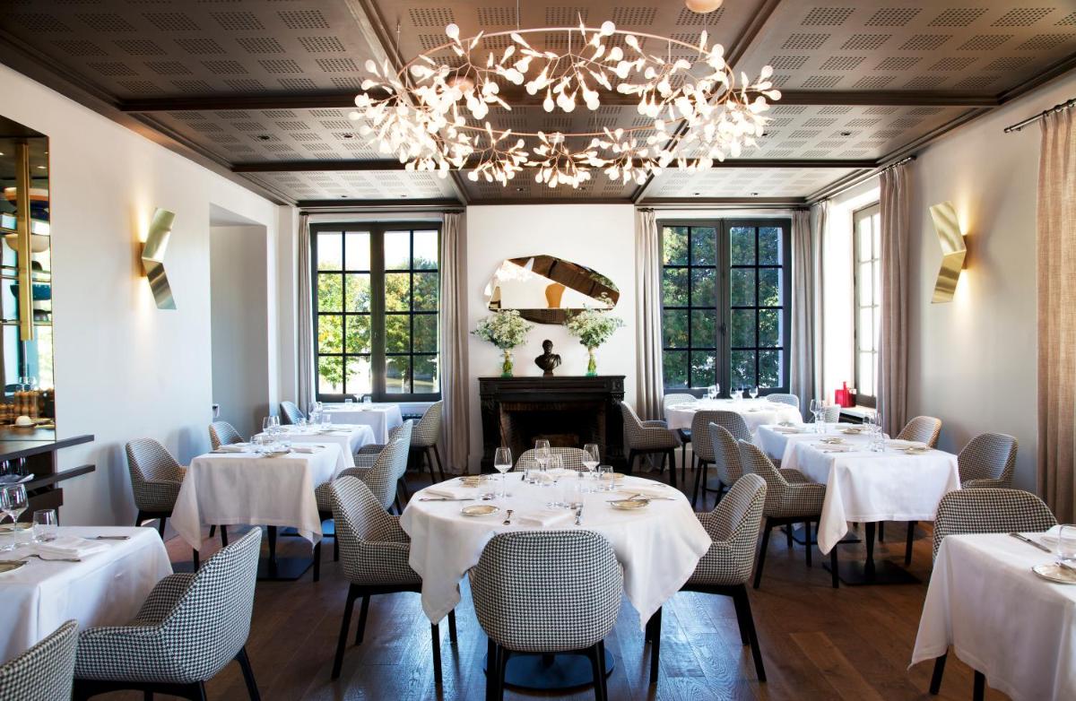 un restaurant avec des tables et des chaises blanches et un lustre dans l'établissement Relais de Chambord, a Small Luxury Hotels of the World, à Chambord