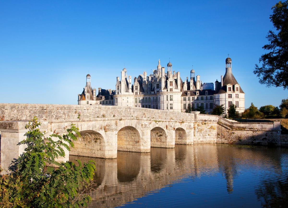 un pont sur une rivière devant un bâtiment dans l'établissement Relais de Chambord, a Small Luxury Hotels of the World, à Chambord