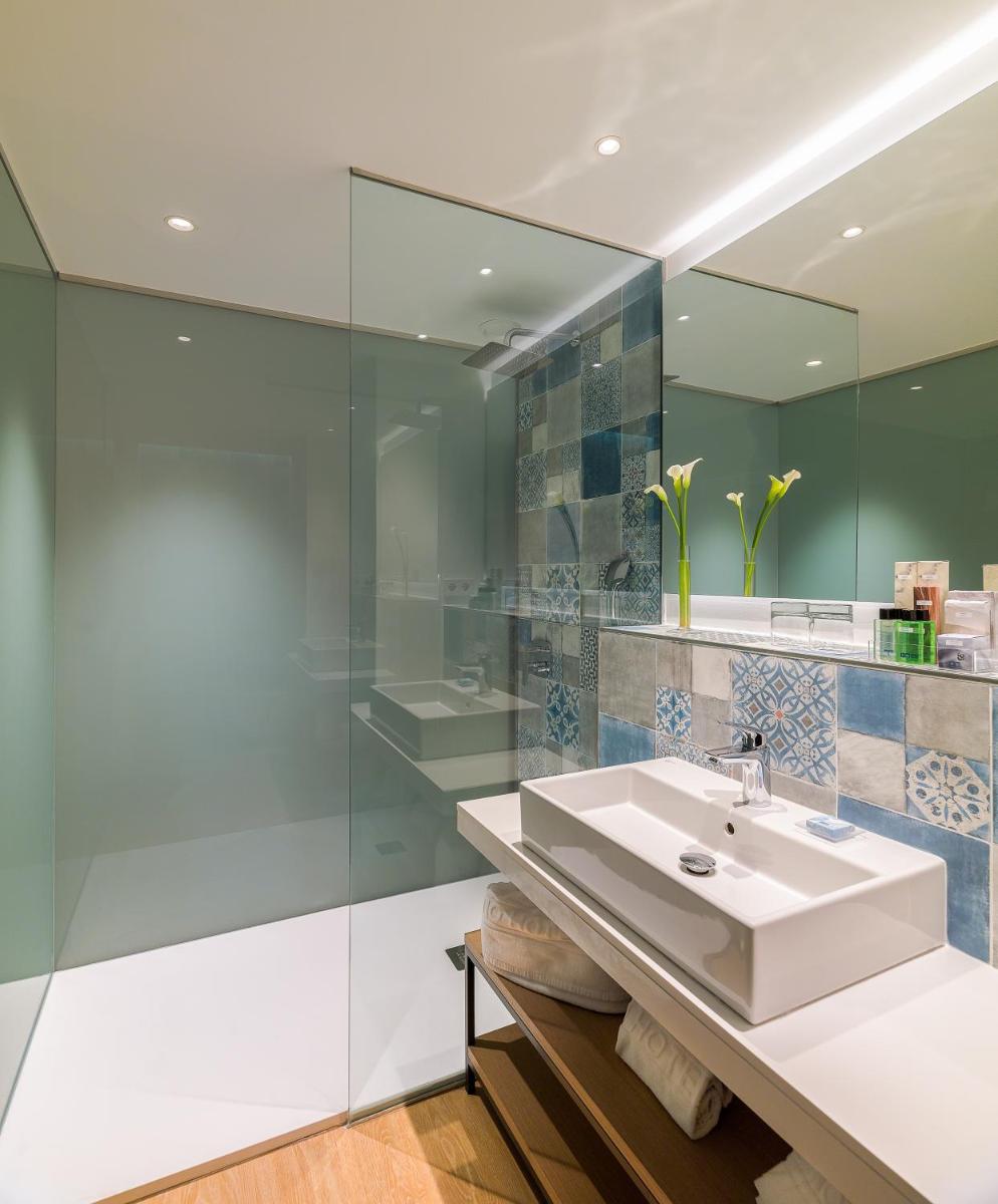 baño con lavabo y pared de cristal en H10 Casa del Mar, en Santa Ponsa
