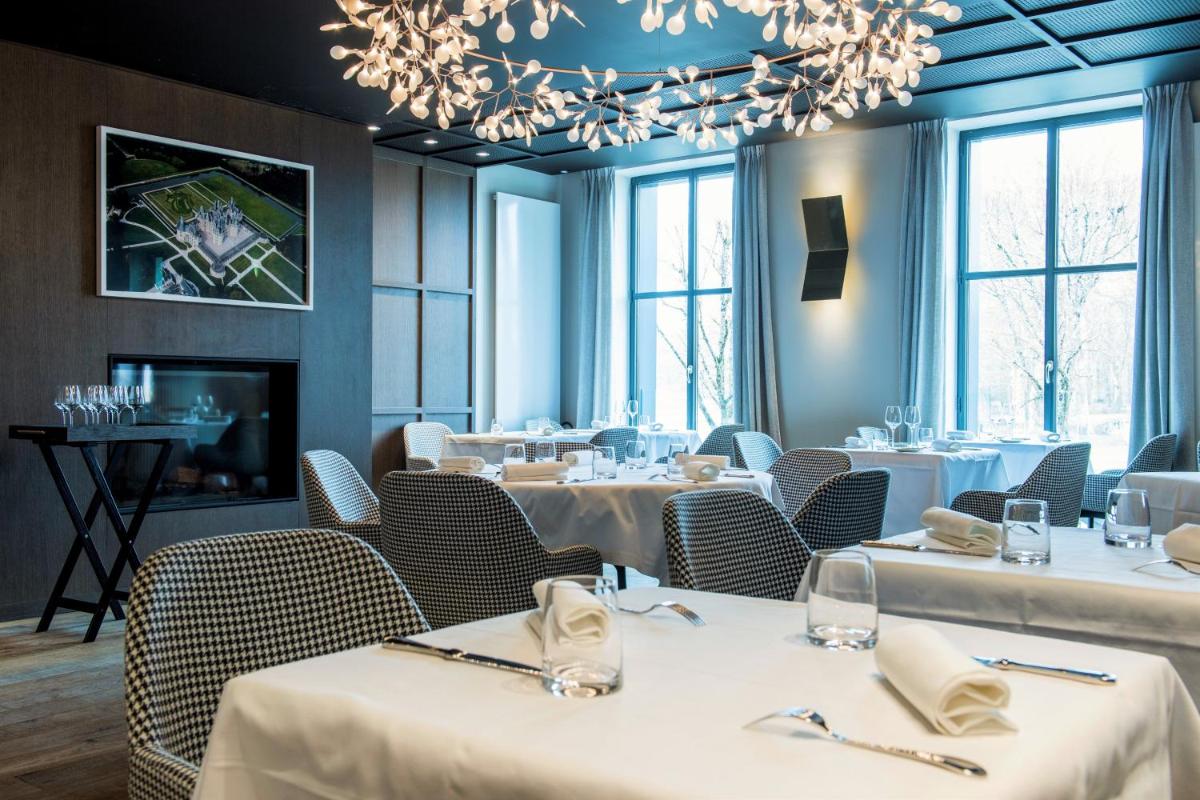 un restaurant avec des tables, des chaises et un lustre dans l'établissement Relais de Chambord, a Small Luxury Hotels of the World, à Chambord