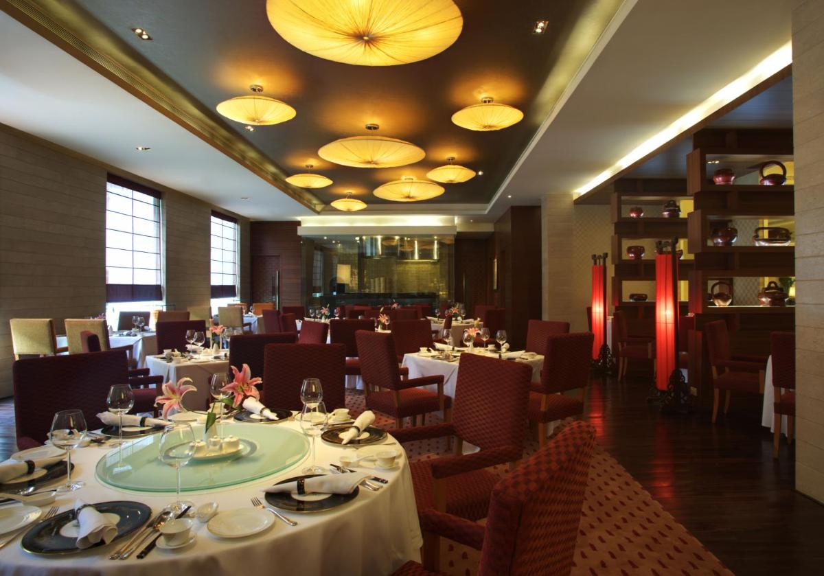 a dining room with tables and chairs and lights at Taj Coromandel in Chennai