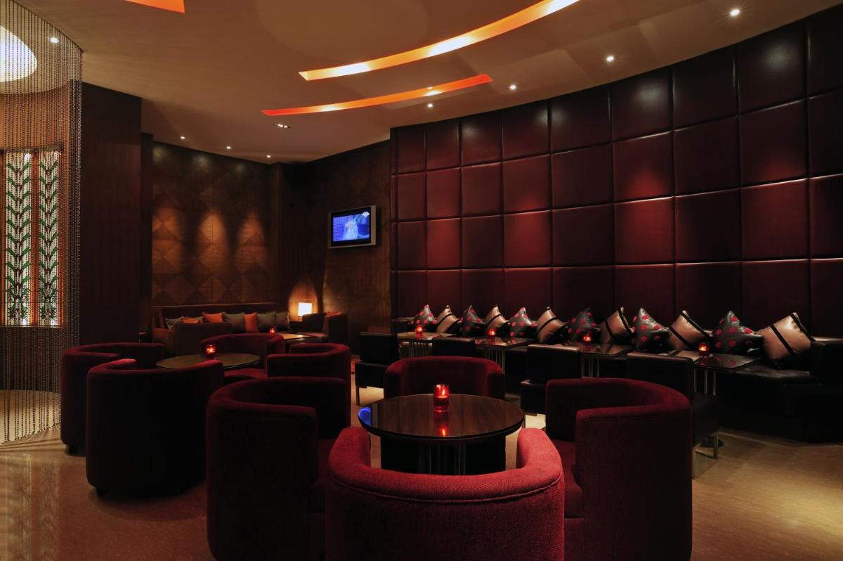 a waiting room with red chairs and a tv at Taj Coromandel in Chennai