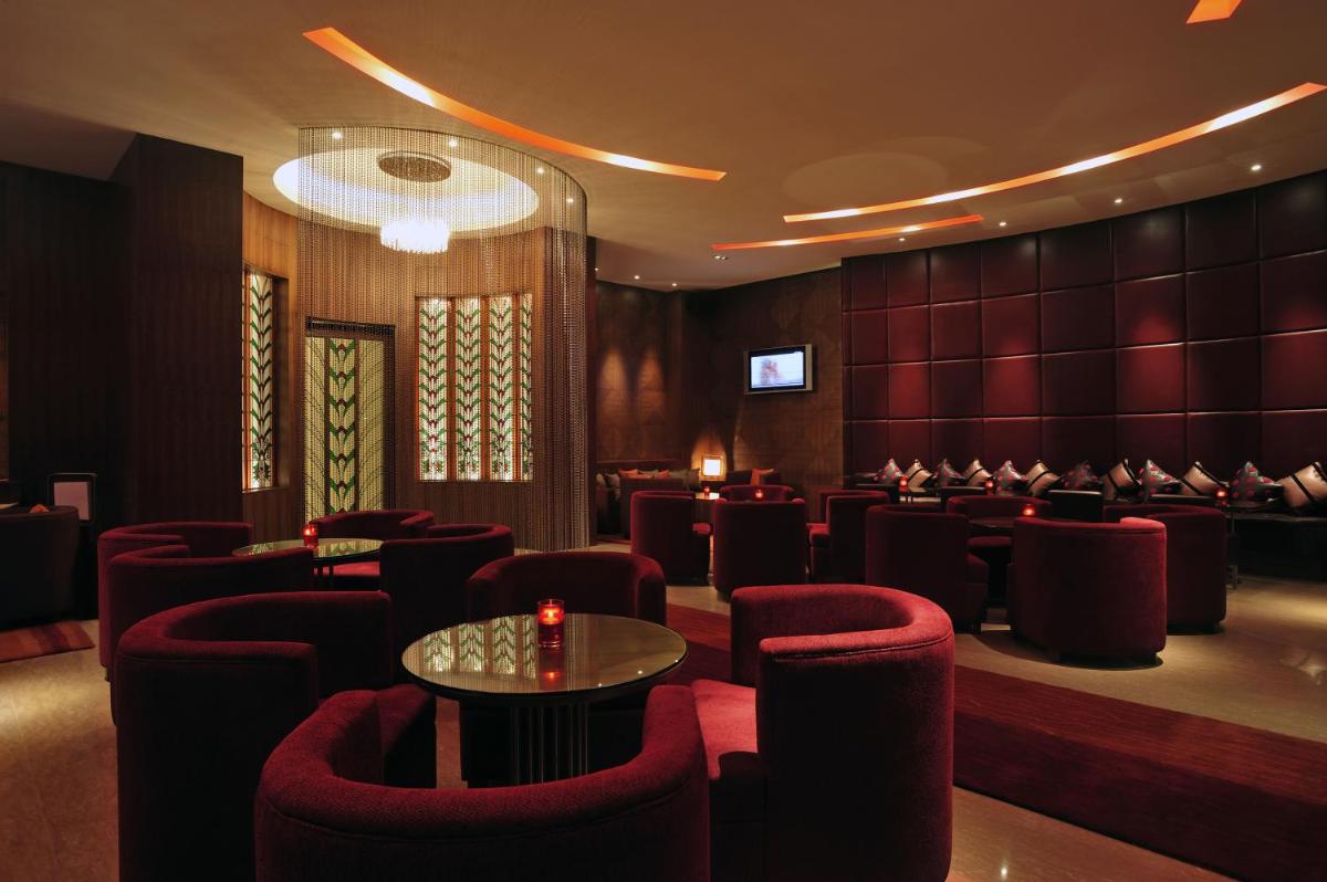a dining room with red chairs and a table at Taj Coromandel in Chennai