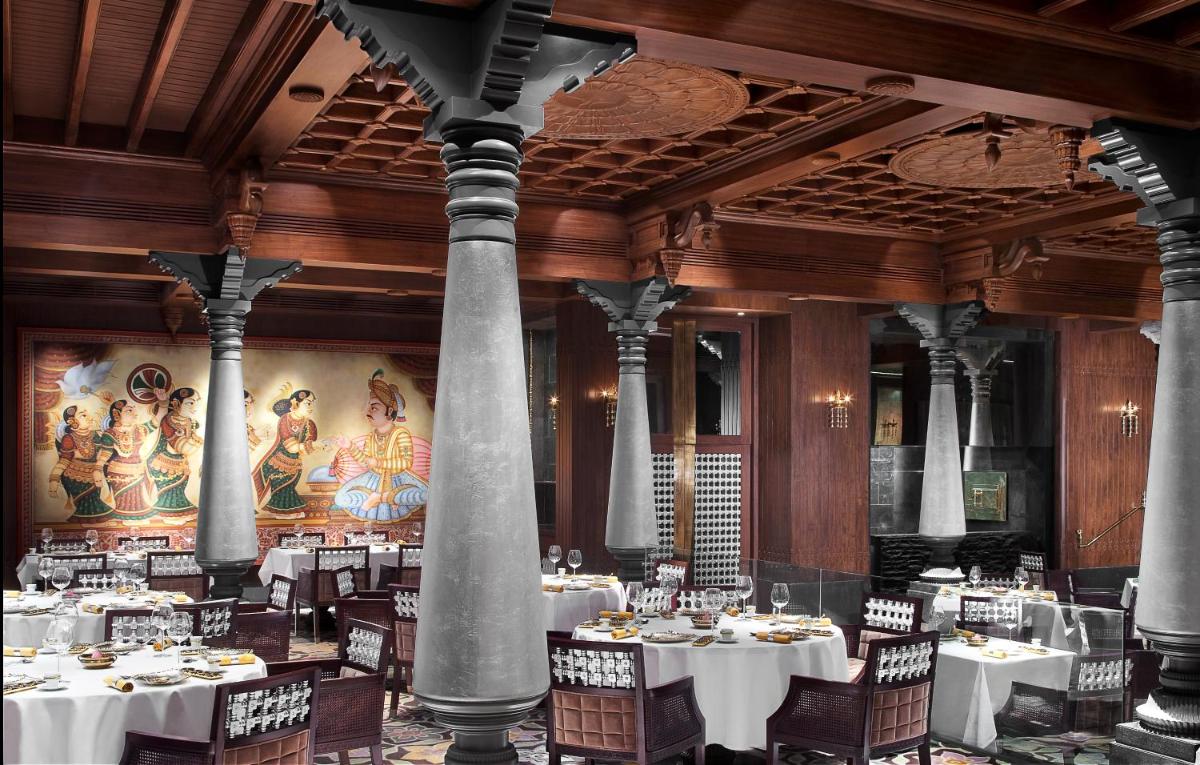 a dining room with tables and chairs and columns at Taj Coromandel in Chennai