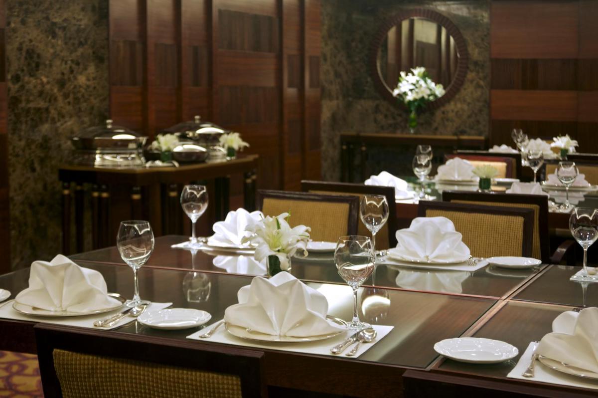 a dining room with a table with glasses and napkins at Taj Coromandel in Chennai