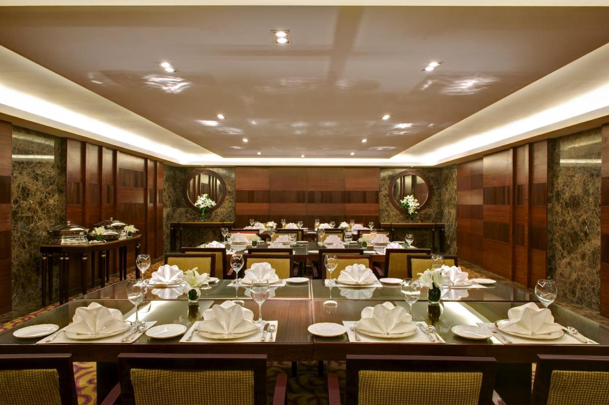 a dining room with a large table and chairs at Taj Coromandel in Chennai