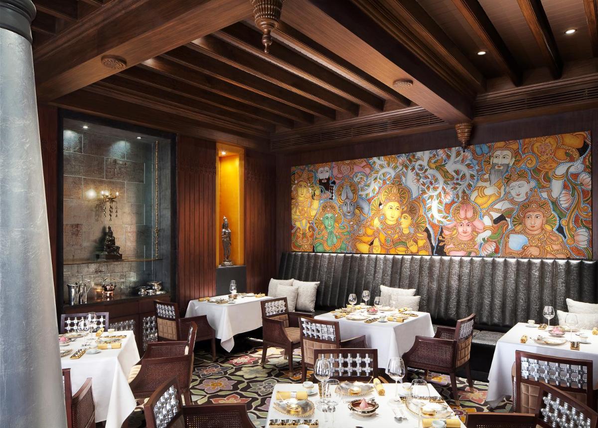 a dining room with tables and a large mural at Taj Coromandel in Chennai