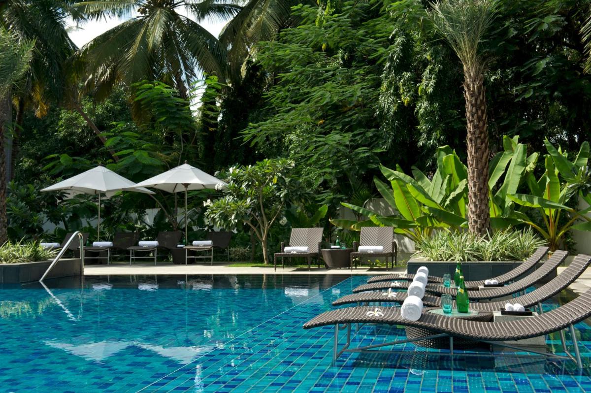 a pool with chaise lounge chairs and a swimming pool at Taj Coromandel in Chennai