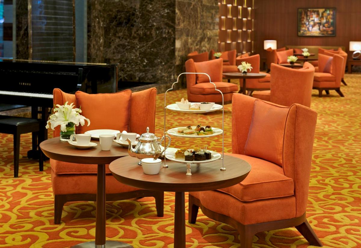 a room with tables and chairs and a piano at Taj Coromandel in Chennai