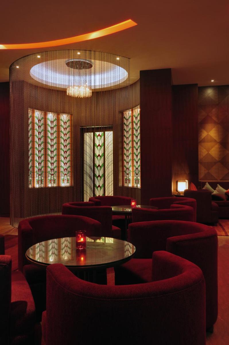 a restaurant with red chairs and a table and a chandelier at Taj Coromandel in Chennai