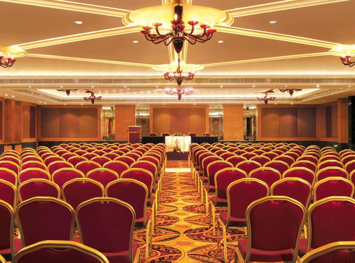 a banquet hall with red chairs and a chandelier at Taj Chandigarh in Chandīgarh