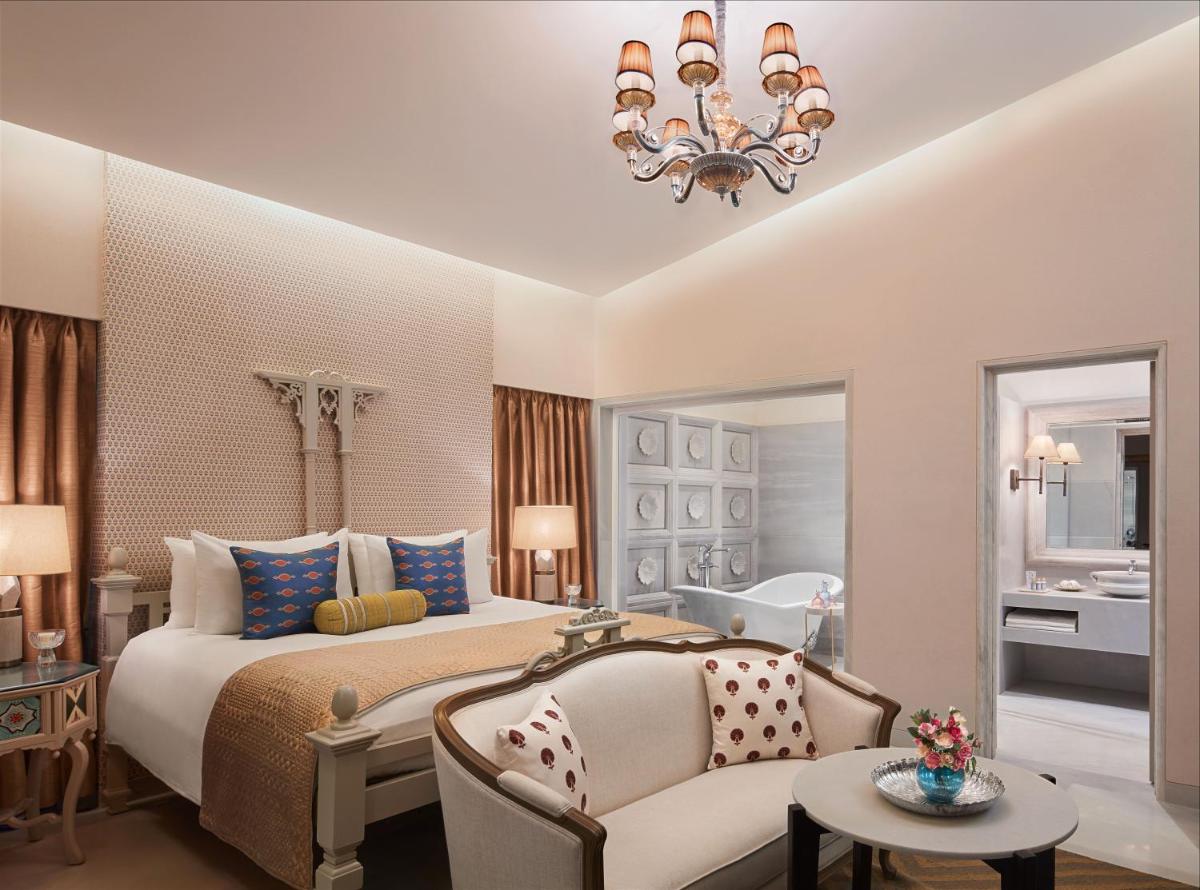 a bedroom with a bed and a couch and a chandelier at Taj Aravali Resort & Spa Udaipur in Udaipur