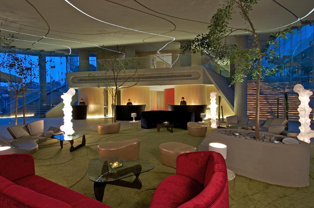 a lobby with red couches and chairs and tables at Vivanta Bengaluru, Whitefield in Bengaluru