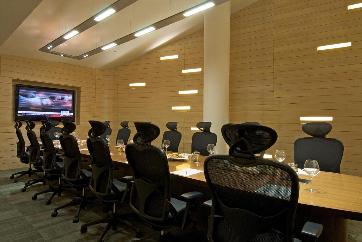 a conference room with a long table and black chairs at Vivanta Bengaluru, Whitefield in Bengaluru